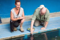 Melissa watches Mark feed a manatee