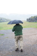 Mark under an umbrella, monoliths in the background