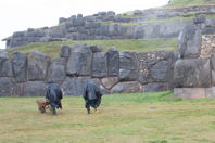 Two workers in raincoats, monoliths in background