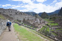 Mark walks toward peaked roofless ruins